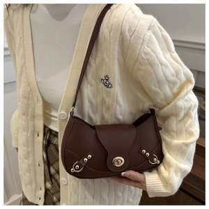 Detail of dark brown leather crescent bag with gold twist lock on ivory knit sweater