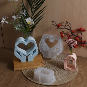 Macro detail of heart-shaped hand and arch vase resin molds with finished plaster crafts