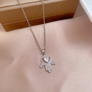 Detailed macro view of silver Hamsa Hand pendant with heart stone and micro-pave zircons