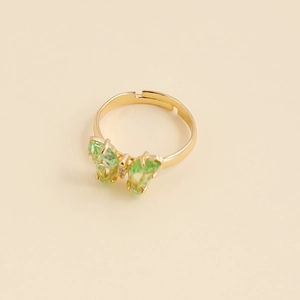 Détail macro de bague ajustable dorée avec papillon en zircon vert et pavé de pierres