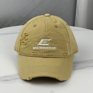 Detailed view of embroidery and distressed edges on a khaki washed cotton baseball cap