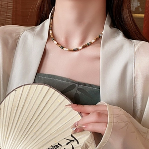 Close-up of a vintage Chinese style beaded necklace with colorful stones on a model