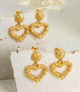 Detail of gold-plated hollow heart earrings with vintage textured twisted lines on stone
