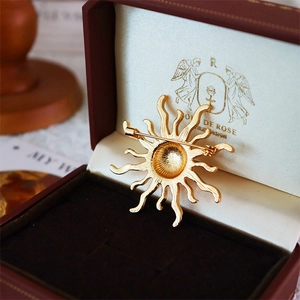 Vintage golden sunburst brooch with radial texture in a premium retro jewelry gift box