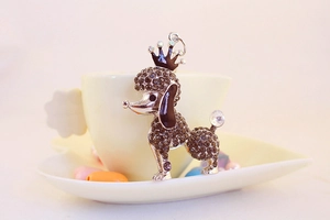 Macro shot of silver poodle keychain with brown rhinestones and black crown detail