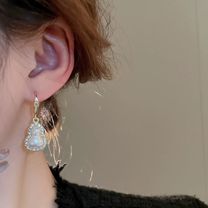 Side view of model wearing gold gourd earrings with inlaid pearls and diamonds