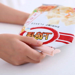 Pink plastic food sealing clip for snack bags, keeping food fresh on white surface