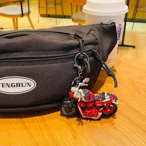 Red and black cartoon alloy motorcycle keychain pendant on a black bag background