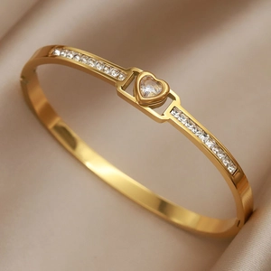 Elegant gold titanium heart bracelet with sparkling zircon stones on silk background