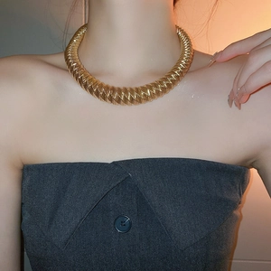 Close-up of a chunky gold twisted link choker necklace worn by a fashion model