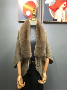 Detail of camel knit poncho showing plush faux fur collar and long fringe hem texture