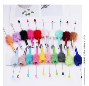 Close-up of assorted colorful DIY beaded pens with soft plush pompoms and metallic barrels