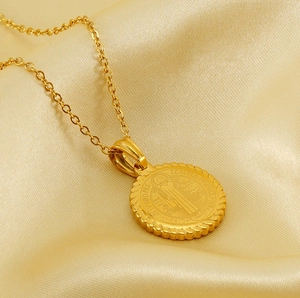 Macro shot of gold St. Benedict religious medallion with rope edge on silk fabric
