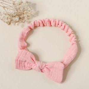 Detail of pink elastic baby headband with large soft textured bow on white surface