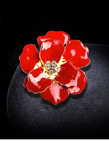 Close-up of red enamel rose brooch with gold edges and sparkling crystal center