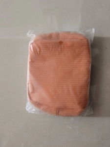 Detail of an orange knitted makeup pouch inside a transparent plastic storage bag