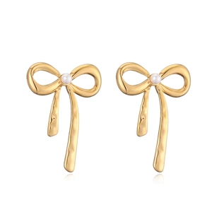 Close-up of golden bow stud earrings featuring elegant white pearl details on white background