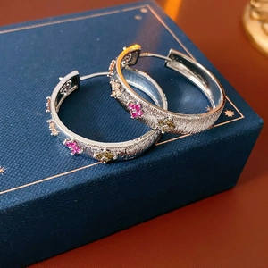 Vue macro des boucles d'oreilles fleurs en zircon argenté sur une boîte à bijoux bleue
