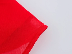 Close-up of red chiffon fabric showing lightweight texture and hem stitching detail