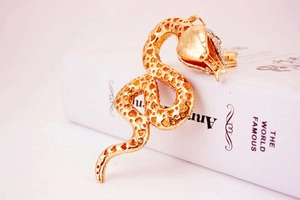 Macro detail of golden snake keychain with heart pattern texture and sparkling rhinestones