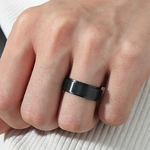 Men's 8mm black spinner ring in 316L stainless steel worn on hand over a soft background