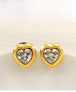 Close-up of heart-shaped gold earrings with zircon stone and beaded edge detail