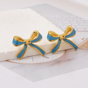 Close-up of sky blue enamel bow earrings with gold plating on a stone prop