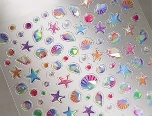 Macro shot of 3D shell and starfish nail stickers with holographic pearl finish
