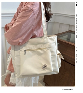 Side view of a white canvas tote bag with side pocket and comfortable shoulder strap