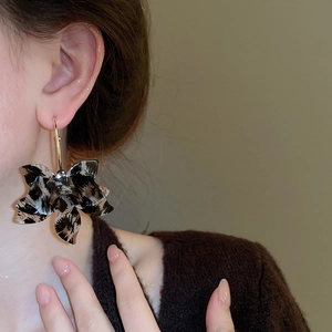 Side view of model wearing large leopard print resin flower hoop earrings