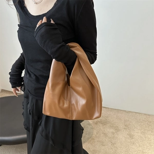 Minimalist caramel PU leather tote bag with elegant handle, shown on model for daily commuting