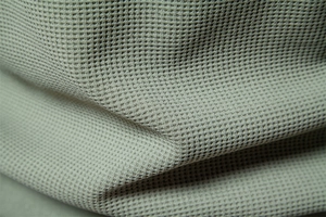 Macro shot of apricot waffle texture knit fabric showing premium weave detail