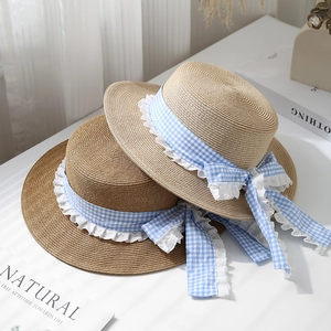 Detail of summer boater hats showing straw texture with blue plaid lace ribbon and bow