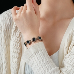 Gros plan d'un bracelet vintage doré avec pierres bleu foncé et fleurs en cristal