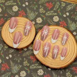 Short oval french press-on nails with white snowflakes and silver glitter on pink base