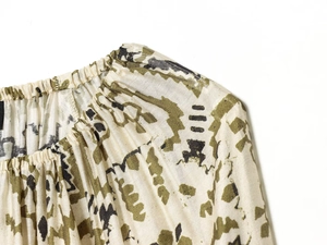 Vue détaillée du col froncé et du motif vert sur une robe surdimensionnée de couleur beige