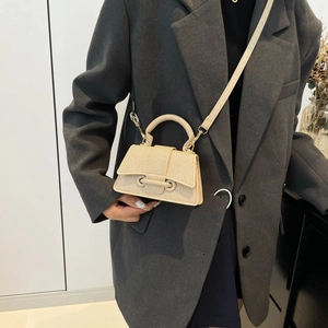 Mini sac à main beige texturé avec poignée et bandoulière porté par un mannequin