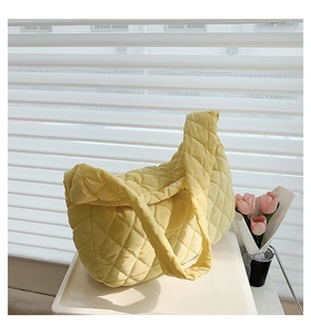 Close-up of yellow quilted cloud bag with diamond stitching beside pink tulips