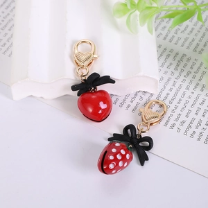 Detailed view of red strawberry and heart charms with bows and golden lobster clasps