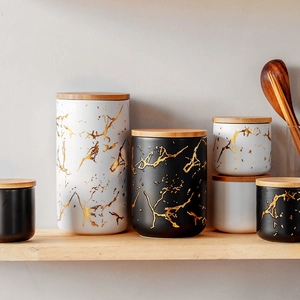 Nordic ceramic food storage jars with golden marble pattern and bamboo lids on shelf