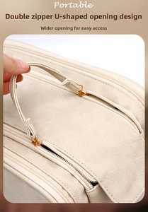 Detail of cream leather makeup bag with gold double zippers and wide U-shaped opening