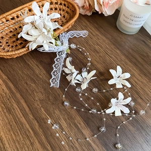 Detailed macro view of white fabric flower hair clip with pearls and lace tassels