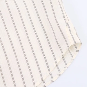 Detailed close-up of a striped shirt hem with curved tailoring and neat stitching work