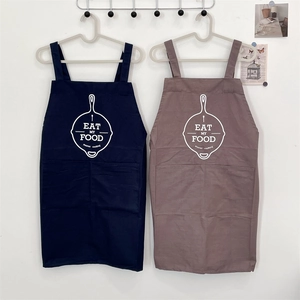 Detail of hanging navy and dusty pink canvas aprons with Eat My Food print and large pockets