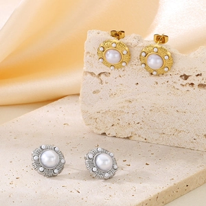 Detail of gold and silver textured round stud earrings with elegant white pearls