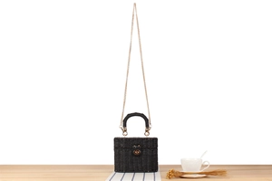 Close-up of black woven box bag with golden twist lock and elegant metallic chain strap