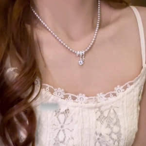 Gros plan d'un collier de perles vintage avec pendentif zircon sur le cou