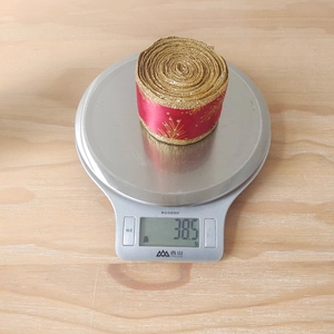 Macro detail of red satin ribbon with gold edges on scale showing 38.5g weight