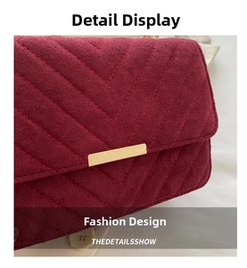 Detail of burgundy suede crossbody bag with V-shaped quilting and golden metal bar