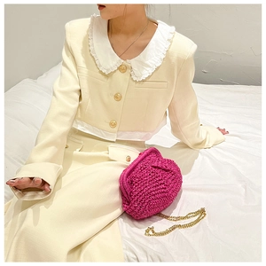 Close-up of pink woven handbag with chain strap styled with chic beige dress set